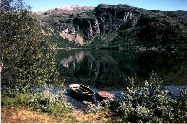 Tranquil Norwegian lake. My rowing boat is moored nearby, and rugged mountains - reflected in the water - form the backdrop to the scene