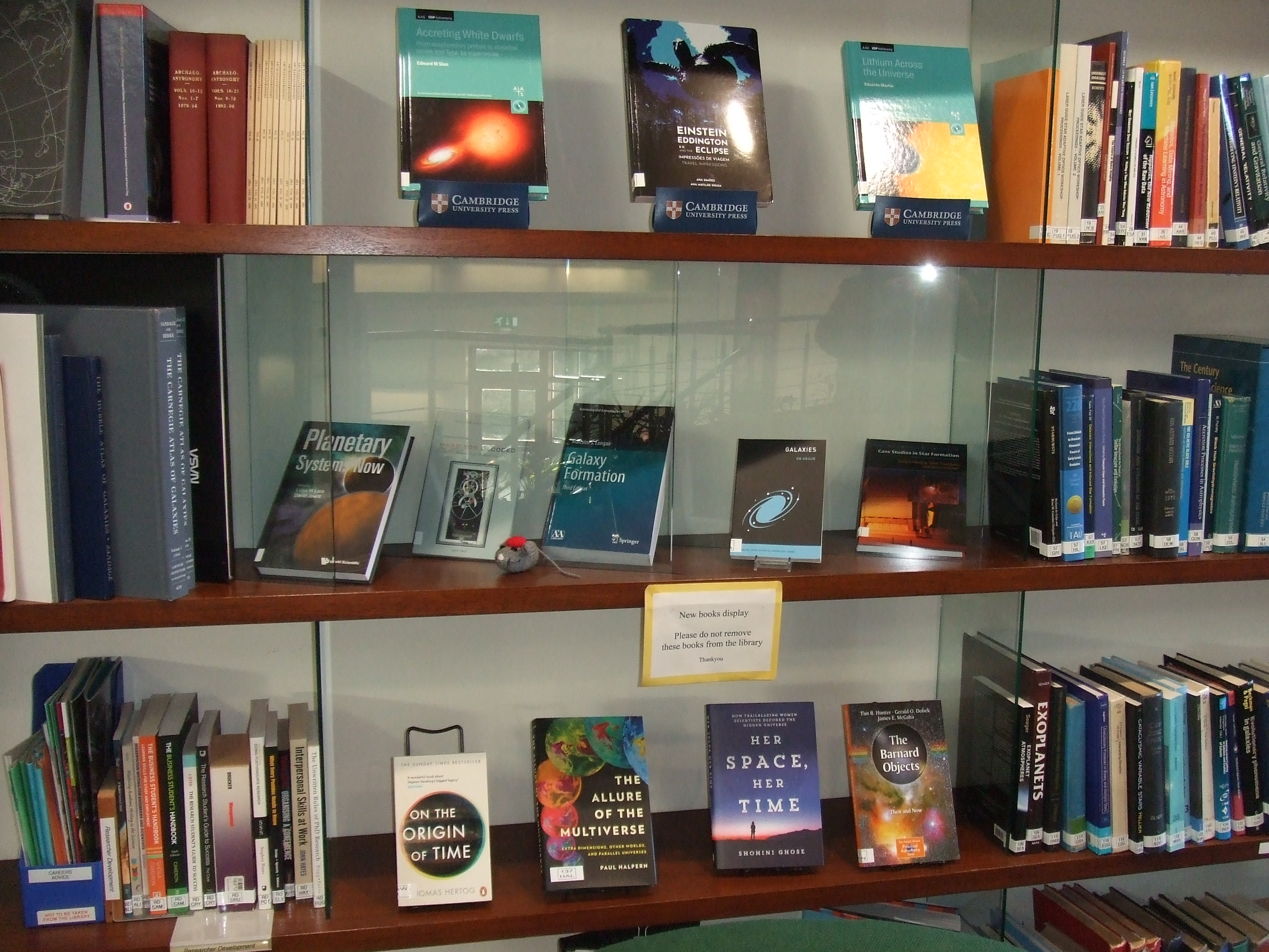 A selection of new astronomy books on three glass shelves